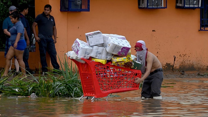 A looter carries a shopping cart full of goods stolen from a supermarket after the passage of Hurricane Otis in Acapulco, Guerrero State, Mexico, on October 25, 2023.