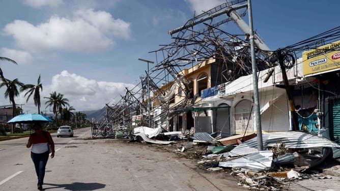 Residents walk past debris in the aftermath of hurricane Otis