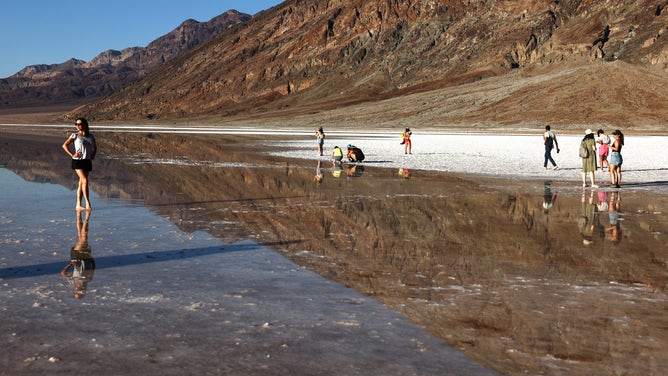 DEATH VALLEY NATIONAL PARK, CALIFORNIA - OCTOBER 21: Visitors gather at the sprawling temporary lake at Badwater Basin salt flats, which was caused by flooding in August from Tropical Storm Hilary, at the recently reopened Death Valley National Park on October 21, 2023 in Death Valley National Park, California. The storm delivered a year’s worth of rain to Death Valley in a single day and flood damage forced the iconic desert park’s closure for eight weeks. Death Valley is the hottest place on Earth and Badwater Basin is located 282 feet below sea level, the lowest elevation in North America. Parts of the park remain closed as repair work continues. (Photo by Mario Tama/Getty Images)