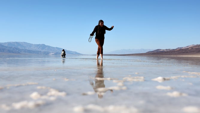 DEATH VALLEY NATIONAL PARK, CALIFORNIA - OCTOBER 21: A visitor walks in the sprawling temporary lake at Badwater Basin salt flats, which was caused by flooding in August from Tropical Storm Hilary, at the recently reopened Death Valley National Park on October 21, 2023 in Death Valley National Park, California. The storm delivered a year’s worth of rain to Death Valley in a single day and flood damage forced the iconic desert park’s closure for eight weeks. Death Valley is the hottest place on Earth and Badwater Basin is located 282 feet below sea level, the lowest elevation in North America. Parts of the park remain closed as repair work continues. (Photo by Mario Tama/Getty Images)