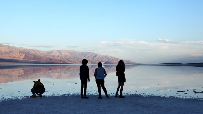 DEATH VALLEY NATIONAL PARK, CALIFORNIA - OCTOBER 23: Visitors view the sprawling temporary lake at Badwater Basin salt flats as the sun rises, which was caused by flooding in August from Tropical Storm Hilary, at the recently reopened Death Valley National Park on October 23, 2023 in Death Valley National Park, California. The storm delivered a year’s worth of rain to Death Valley in a single day and flood damage forced the iconic desert park’s closure for eight weeks. Death Valley is the hottest place on Earth and Badwater Basin is located 282 feet below sea level, the lowest elevation in North America. Parts of the park remain closed as repair work continues. (Photo by Mario Tama/Getty Images)