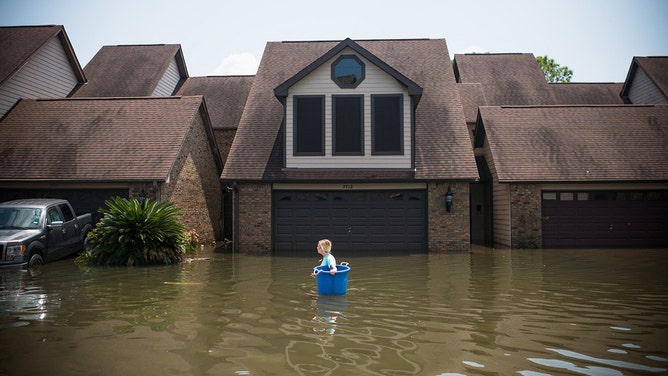 Jenna Fountain carries a bucket down Regency Drive to try to recover items from their flooded home in Port Arthur, Texas, September 1, 2017, following Hurricane Harvey.