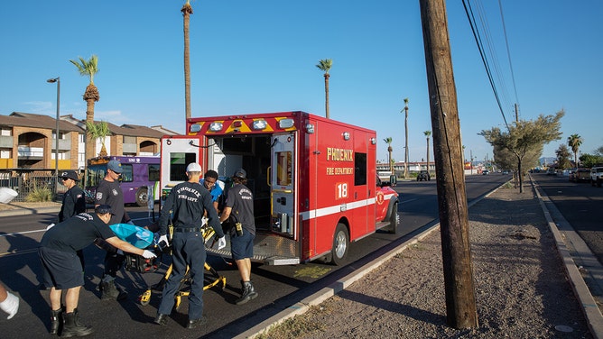 FILE -- Firefighters and paramedics from Phoenix Fire Station 18 wheel a resident to an ambulance from a bus stop during a heat wave in Phoenix, Arizona, on Thursday, July 20, 2023.