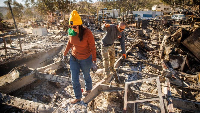 Relatives walk through the remains of their family's home after it was destroyed during the Highland Fire in Aguanga, California, US, on Tuesday, Oct. 31, 2023.