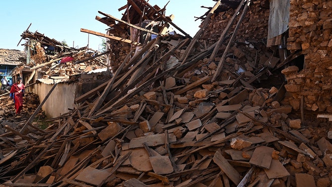 People walk through ruins of houses in the aftermath of an earthquake at Jajarkot district on November 4, 2023.