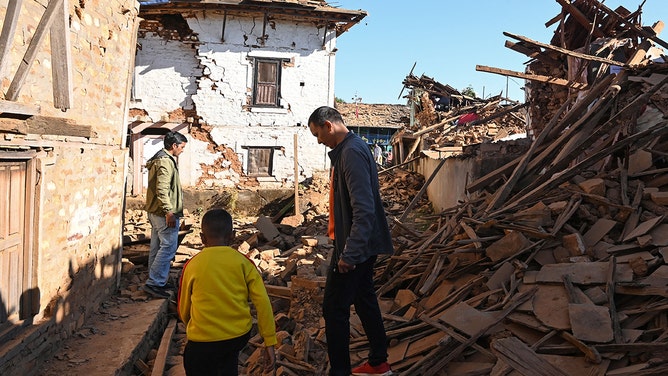 People walk through ruins of houses in the aftermath of an earthquake at Jajarkot district on November 4, 2023.