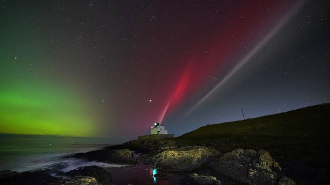 The aurora borealis (left) alongside a strong thermal emission velocity enhancement, a rare aurora-like phenomenon named a STEVE in 2016 by scientists in Canada, can be seen over Bamburgh castle, in Northumberland on the North East coast of England. The atmospheric optical phenomenon is caused by a flowing ribbon of hot plasma breaking through into the earth's ionosphere, appearing in the sky as a purple, red and white arc. Picture date: Sunday November 5, 2023. (Photo by Owen Humphreys/PA Images via Getty Images)