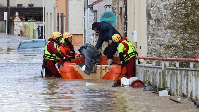 French firefighters help a local resident to evacuate in a flooded street during a rescue operation in Isques, near Boulogne-sur-Mer, northern France on November 7, 2023.