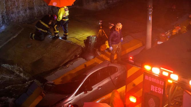 Rescuers search for people trapped under a wall that collapsed on several vehicles after heavy rains on 27 de Febrero Avenue in Santo Domingo on November 18, 2023. (Photo by Felix Leon / AFP) (Photo by FELIX LEON/AFP via Getty Images)