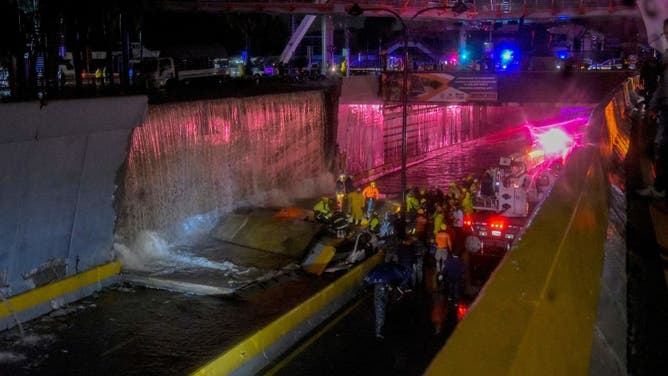 Rescuers search for people trapped under a wall that collapsed on several vehicles after heavy rains on 27 de Febrero Avenue in Santo Domingo on November 18, 2023. (Photo by Felix Leon / AFP) (Photo by FELIX LEON/AFP via Getty Images)