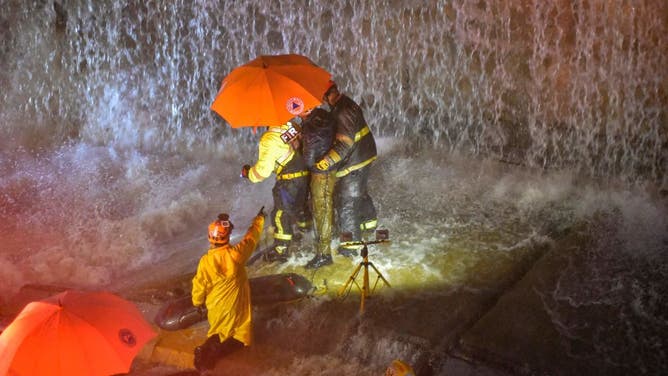 Rescuers search for people trapped under a wall that collapsed on several vehicles after heavy rains on 27 de Febrero Avenue in Santo Domingo on November 18, 2023. (Photo by Felix Leon / AFP) (Photo by FELIX LEON/AFP via Getty Images)