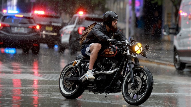 A motorcyclist drives through a rain storm on November 15, 2023 in Miami Beach, Florida.