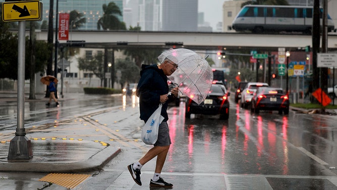 A pedestrian crosses the street in a rain storm on November 15, 2023 in Miami, Florida.