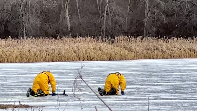 The firefighters crawl over the ice.