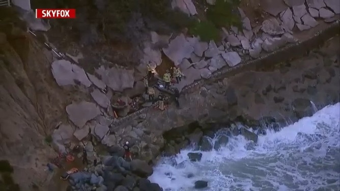 Crews work to rescue a man after he fell into a hole on the side of a cliff in San Diego, California, on Dec. 22, 2023.