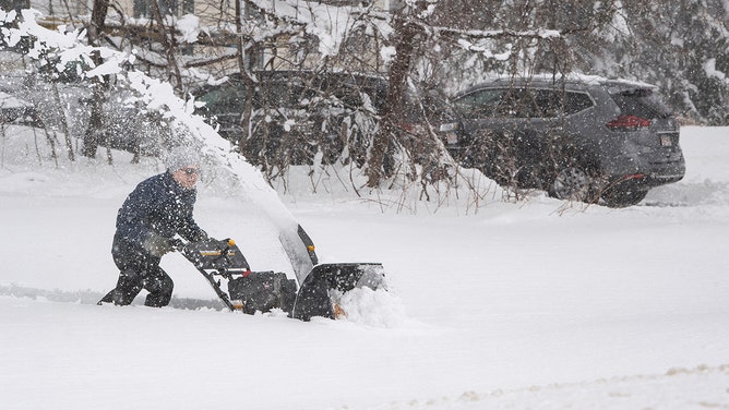  A person tries to use a snowblower to clear snow from their driveway, over a foot deep, during a noreaster in Rutland, Massachusetts on March 14, 2023.