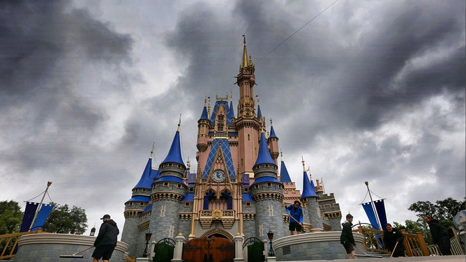 Cast members squeegee the stage in front of Cinderella Castle as rain bands pass through the Magic Kingdom at Walt Disney World, in Lake Buena Vista, Florida, on Aug. 30, 2023.