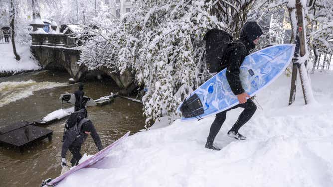 Onset of winter in southern Germany - Munich 02 December 2023, Bavaria, Munich: Two men carry their surfboards up the embankment at the Eisbach in the English Garden. Photo: Peter Kneffel/dpa (Photo by Peter Kneffel/picture alliance via Getty Images)