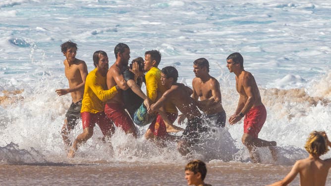 People carry Brazilian surfer Joao Chianca who wiped out while practicing for the upcoming Vans 2023 Pipeline Masters event at Banzai Pipeline in Haleiwa, Oahu's north shore, Hawaii, on December 3, 2023.