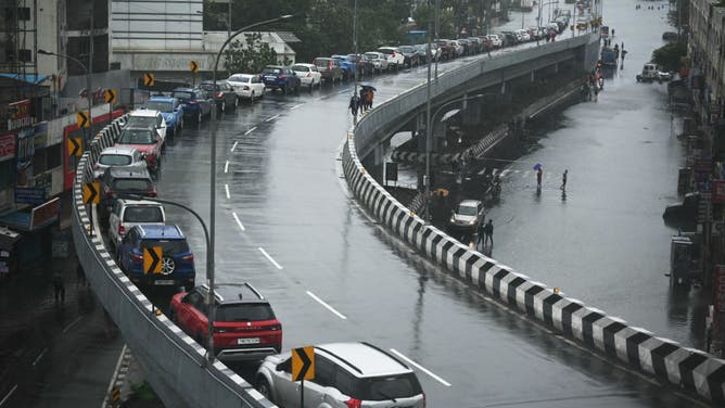 Cars are seen parked on a flyover by local residents next to a flooded street after heavy rains in Chennai on December 4, 2023.