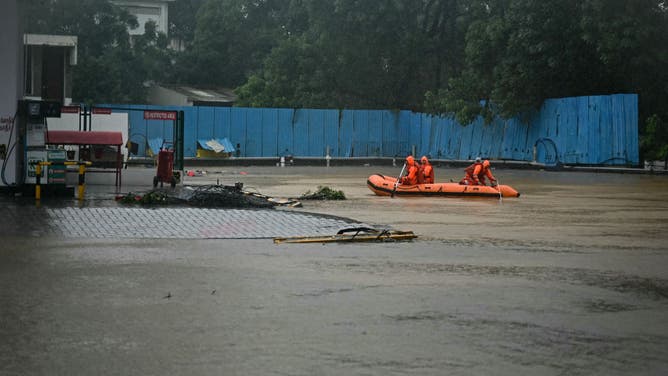 National Disaster Response Force (NDRF) personnel row a boat through a flooded street, during a rescue operation to help trapped civilians following heavy rainfall in Chennai on December 4, 2023.