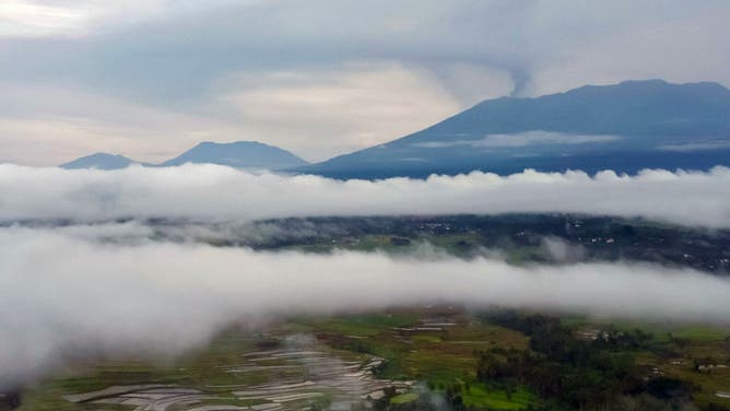 Widok z lotu ptaka pokazuje górę Marabi (w tle po prawej) wyrzucającą popiół wulkaniczny podczas erupcji, jak widać z Padusangar w Agam na Zachodniej Sumatrze o świcie 6 grudnia 2023 r.