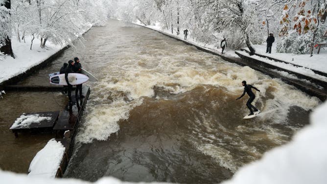 A surfer surfs on the current of the Eisbach River following a heavy snowfall on December 02, 2023 in Munich, Germany.