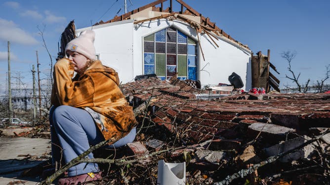 A young person sits on the collapsed wall of Sabbath Day Church of God in Christ in the aftermath of a tornado on December 10, 2023 in Madison, Tennessee.