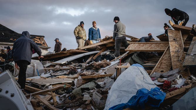 Residents and visitors work to clear debris in search of pets and belongings of a destroyed home in the aftermath of a tornado on December 10, 2023 in Clarksville, Tennessee.