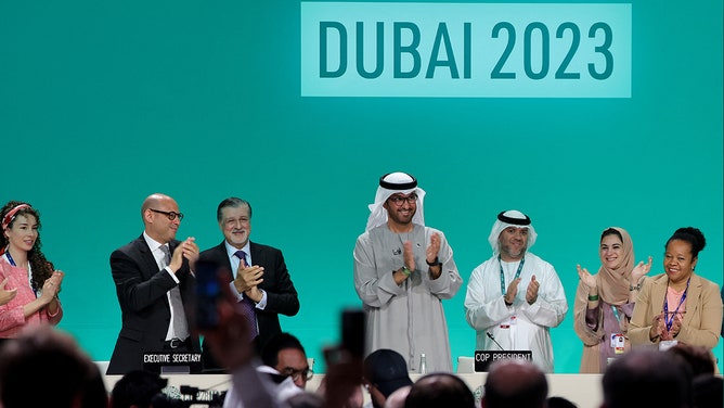 COP28 president Sultan Ahmed Al Jaber (center) applauds among other officials before a plenary session during the United Nations climate summit in Dubai on December 13, 2023.