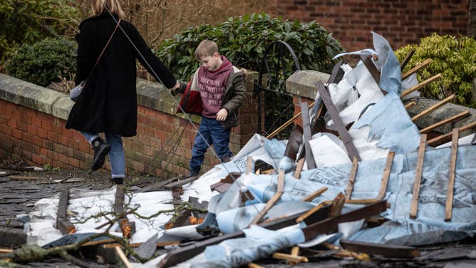 A woman and child step over debris in the aftermath of a tornado on December 28, 2023 in Stalybridge, England. 