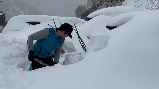 A man shovels snow from around a vehicle in Little Cottonwood Canyon, Utah. Dec. 4, 2023.