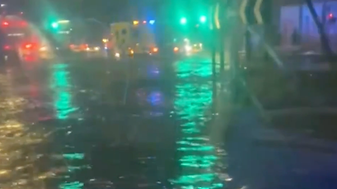 Lights reflect off of flood water filling a roundabout.