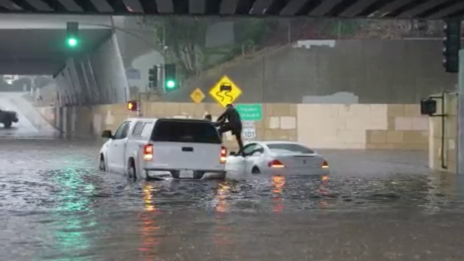 A Good Samaritan pulls a driver and child passenger from a BMW trapped in floodwaters on Thursday, Dec. 21,