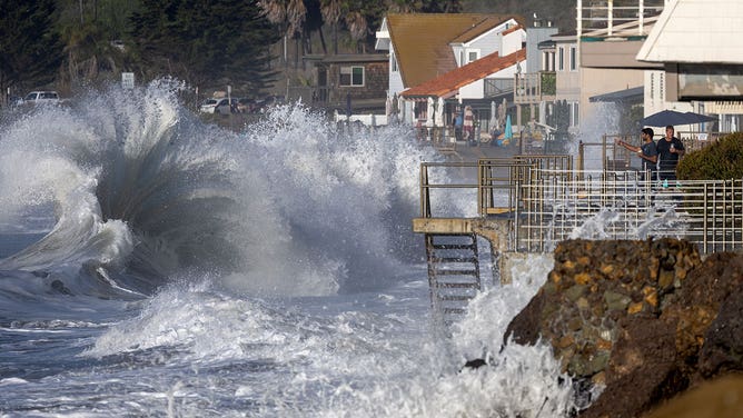 Men watch from a balcony in Faria Beach as huge waves crash on the shore Thursday, Dec. 28, 2023 in Ventura, CA.