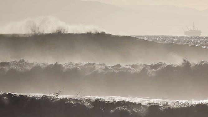Large waves break near the beach with an oil platform in the distance on December 28, 2023, in Ventura, California.