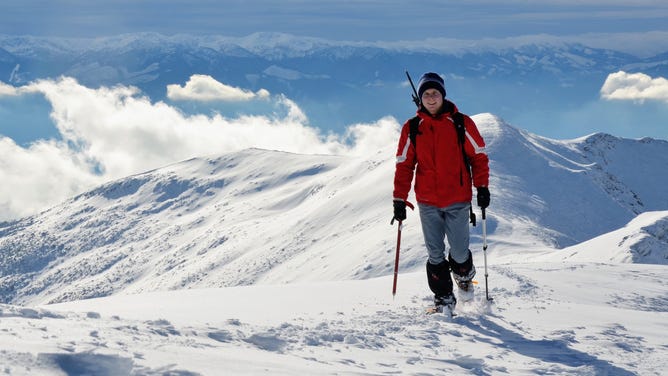 Man hikes a snowy mountain.