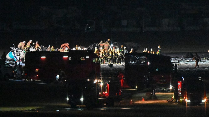 Rescue crews work at the site where a Japan coast guard aircraft collided with a Japan Airlines (JAL) passenger plane on the tarmac at Tokyo International Airport at Haneda on January 2, 2024. Five people aboard the Japan coast guard aircraft died on January 2 when it hit the Japan Airlines passenger plane on the ground in a fiery collision at Haneda airport. (Photo by Richard A. Brooks / AFP) (Photo by RICHARD A. BROOKS/AFP via Getty Images)