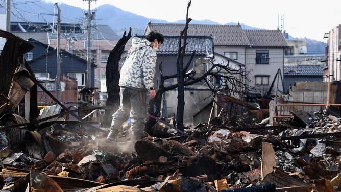 A man looks through the burned Wajima Asa-ichi, or morning market area, in the city of Wajima, Ishikawa prefecture, on January 5, 2024, after a major 7.5 magnitude earthquake struck the Noto region on New Year's Day. The death toll from a devastating earthquake in central Japan rose to 92 on January 5, regional authorities said, with the number of missing jumping to 242. (Photo by Toshifumi KITAMURA / AFP) (Photo by TOSHIFUMI KITAMURA/AFP via Getty Images)