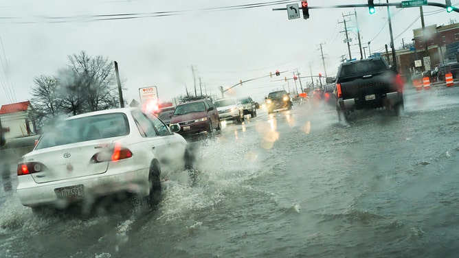 Cars make their way through flooding at the intersection of University Blvd. and New Hampshire Ave. in Langley Park, MD.