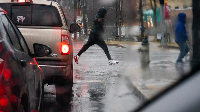 A pedestrian leaps over a puddle at the intersection of Piney Branch Rd. And Flower Ave. in Takoma Park, MD.