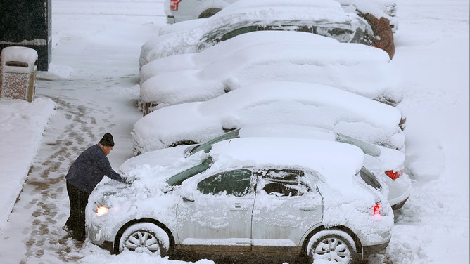 A person clears the snow from his vehicle as a snowstorm dumps several inches of snow on the area on January 09, 2024 in Des Moines, Iowa.