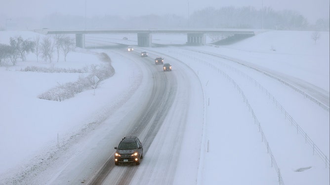 Vehicles drive slowly along I-80 as a snowstorm dumps several inches of snow on the area on January 09, 2024, in Des Moines, Iowa.