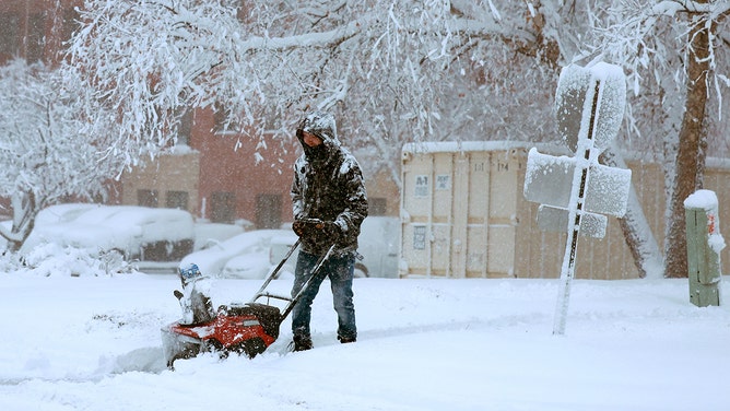 A person uses a snowblower to clear a sidewalk as a snowstorm dumps several inches of snow on the area on January 09, 2024 in Des Moines, Iowa.