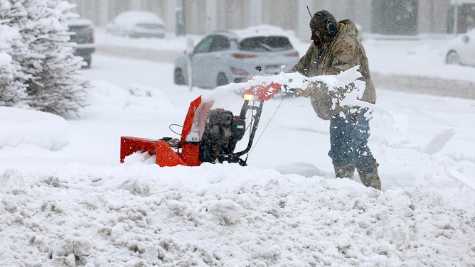 A person uses a snowblower to clear a sidewalk as a snowstorm dumps several inches of snow on the area on January 09, 2024 in Des Moines, Iowa.