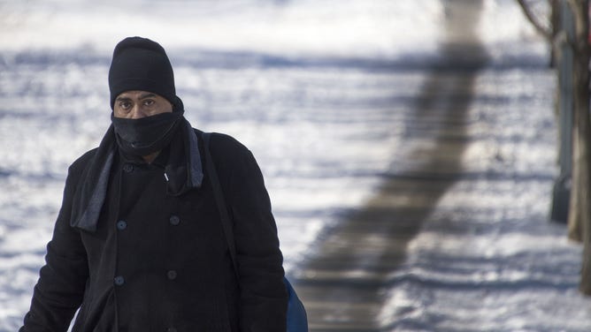 FILE - A man walks through the snow with a scarf over his face in Washington, DC, on January 8, 2014, as dry and unseasonably cold weather hits the area. An Arctic blast sweeping Canada and parts of the United States this week closed schools, grounded jets, killed at least four people, and even shook the ground. AFP PHOTO/JIM WATSON (Photo credit should read JIM WATSON/AFP via Getty Images)