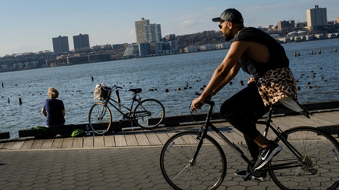 People ride bikes along the Hudson River on an unseasonably warm afternoon, February 21, 2018 in New York City.