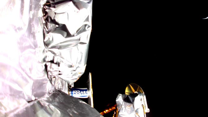 Image from the Peregrine spacecraft in space shows the Pocari Sweat time capsule and in the upper right corner a sliver of Earth as seen by the spacecraft.