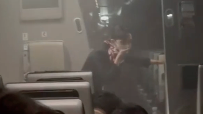 A flight attendant in a smoky cabin.