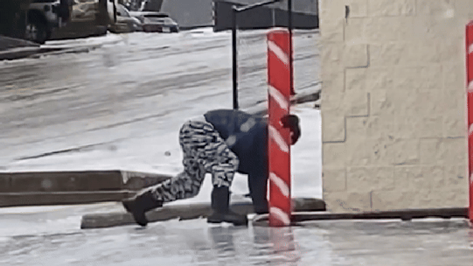 A person struggles to stand on the icy concrete.